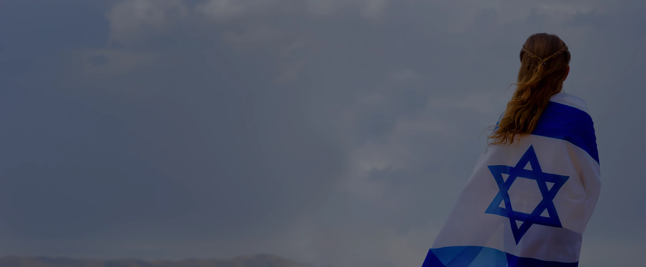 Person looking straight to a sky background while covering their back with the Israeli flag